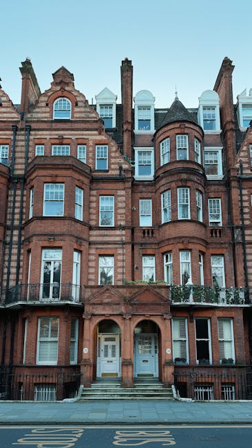 Photograph of a multi-storey Victorian residential building constructed with red brick and stone detailing, located on a narrow street in Belgravia. The building features large sash windows with white