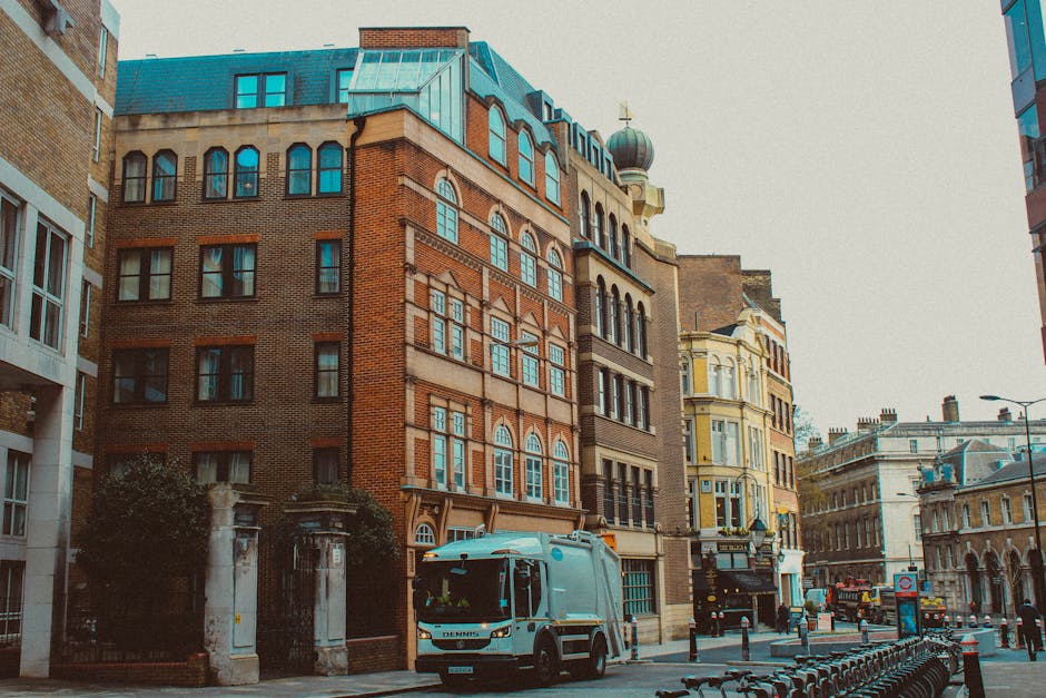 A white removal van with the company branding 'Man With a Van Westminster' is parked on a busy street in Pimlico, Westminster, during the daytime. The van is positioned in front of a row of multi-stor